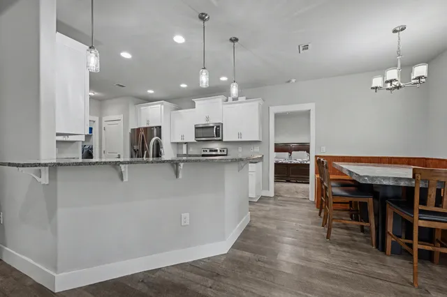 a kitchen with stainless steel appliances granite countertop a refrigerator a stove and a wooden floors