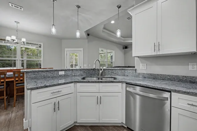 a kitchen with white cabinets and chandelier