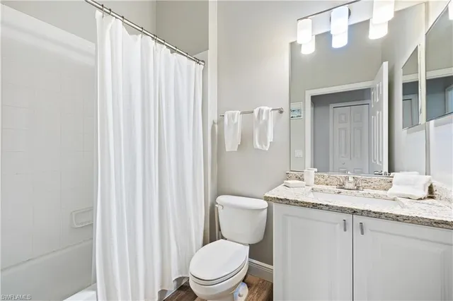 a bathroom with a granite countertop toilet sink and mirror