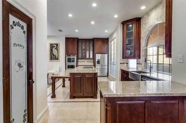 a kitchen with granite countertop kitchen island stainless steel appliances a sink stove and cabinets