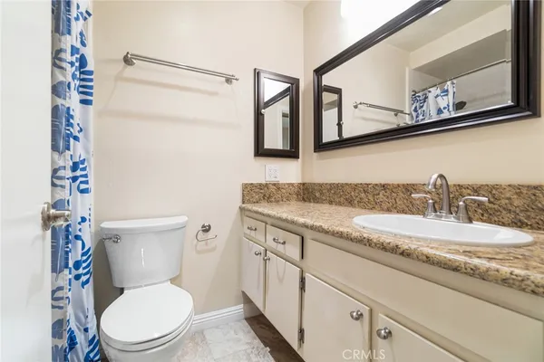 a bathroom with a granite countertop toilet sink and mirror
