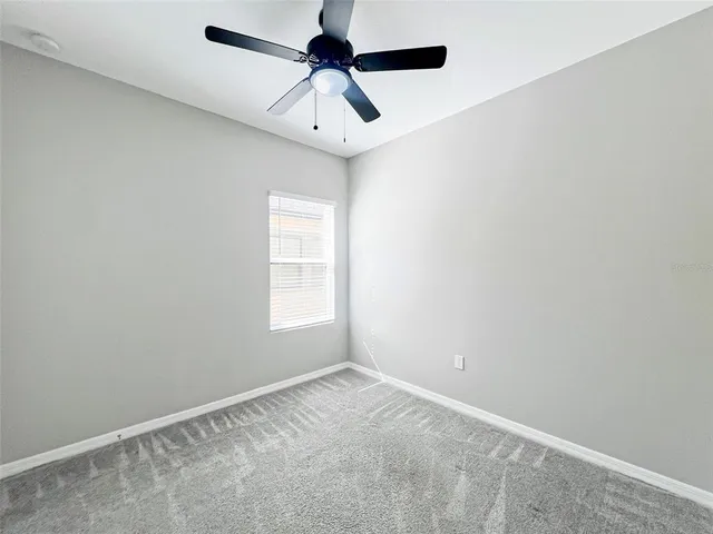 an empty room with a window and a fan