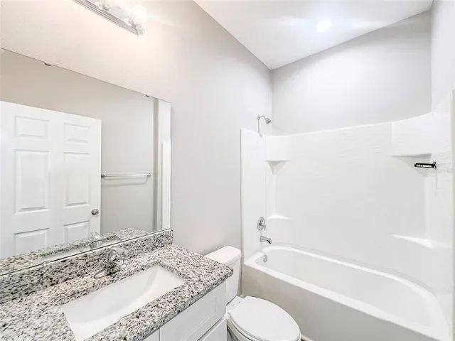 a bathroom with a granite countertop tub sink and toilet