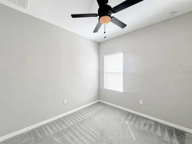 an empty room with a window and a fan