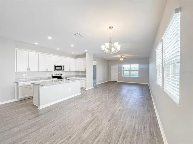 a large kitchen with hardwood floor sink stainless steel appliances and window