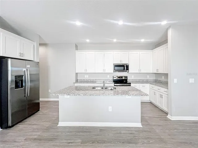 a kitchen with stainless steel appliances granite countertop a refrigerator sink and microwave