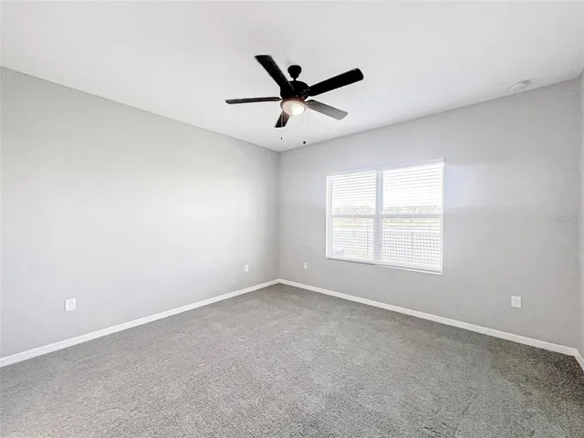 an empty room with a window and a fan