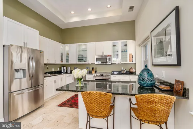 a kitchen with stainless steel appliances granite countertop a refrigerator a stove a sink dishwasher a dining table and chairs with wooden floor