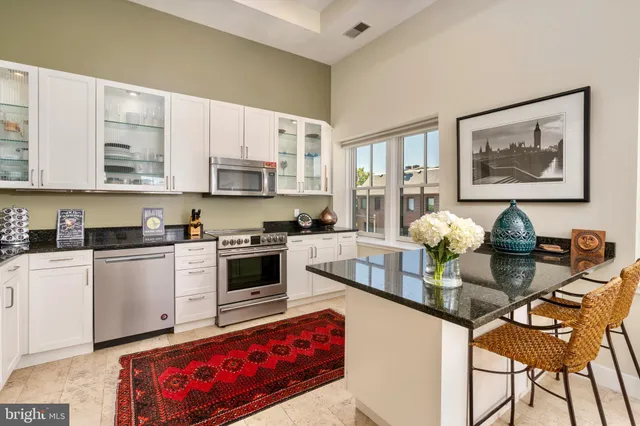 a kitchen with stainless steel appliances a stove a sink cabinets and a window