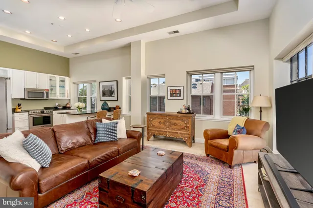 a living room with furniture a flat screen tv and a refrigerator
