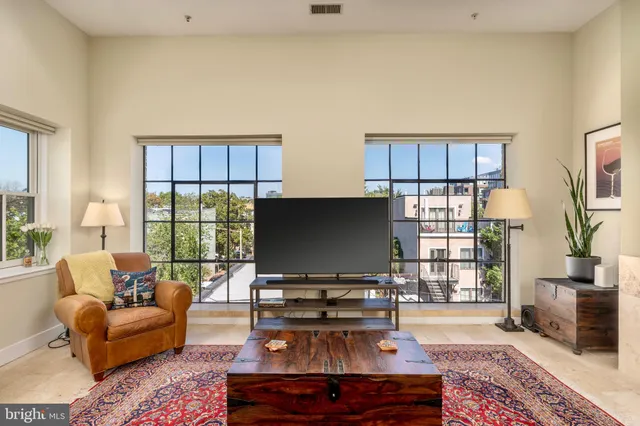 a living room with furniture a flat screen tv and a floor to ceiling window