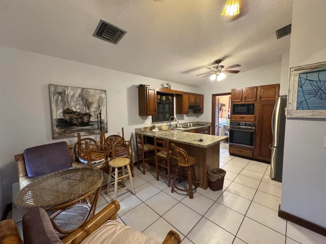 a living room with stainless steel appliances furniture a kitchen view and a refrigerator