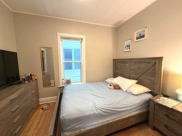 a bedroom with a bed and a flat tv screen on dresser