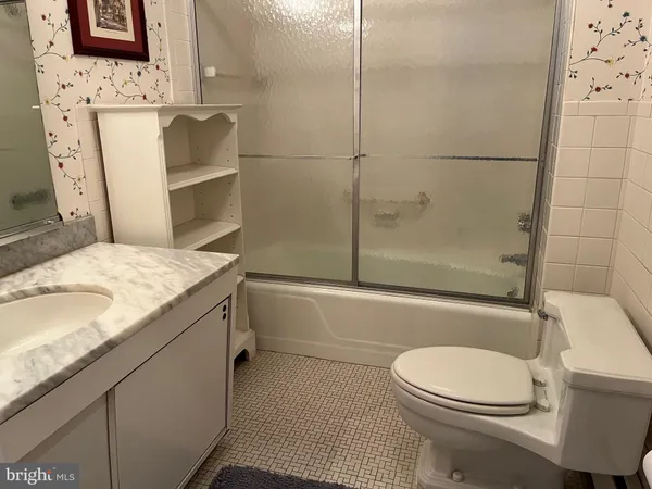 a bathroom with a granite countertop bathtub sink vanity mirror and toilet
