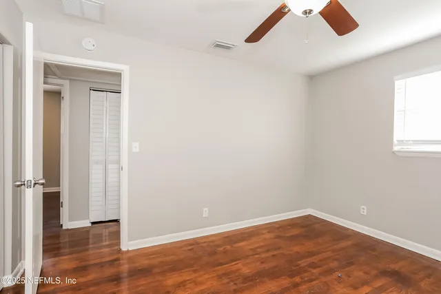 an empty room with wooden floor cabinet and windows