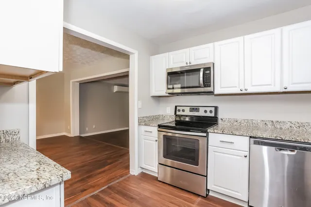 a kitchen with granite countertop wooden cabinets stainless steel appliances and a sink