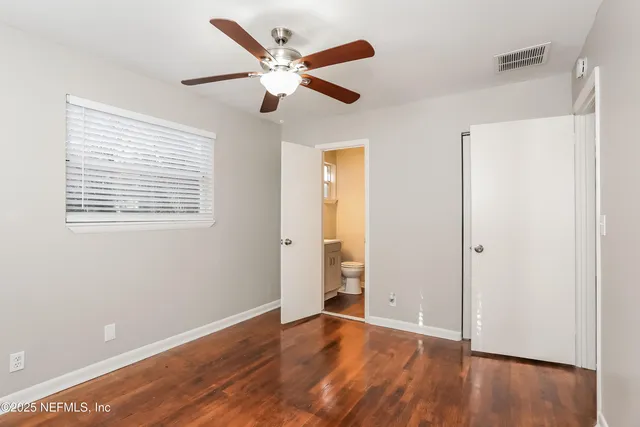 a view of an empty room with wooden floor and a ceiling fan