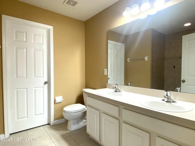 a bathroom with a double vanity sink toilet and a mirror