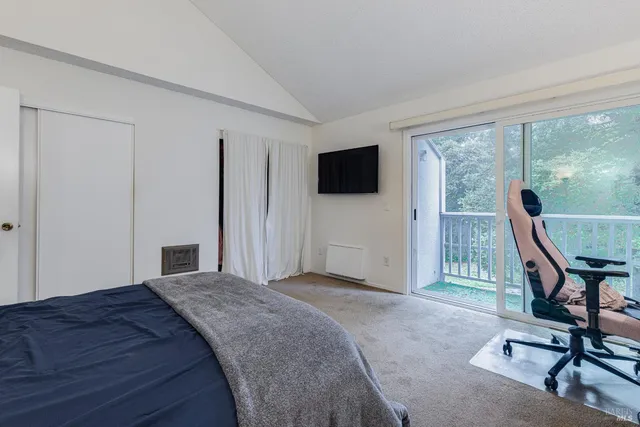 a bedroom with a bed and a flat tv screen next to a large window