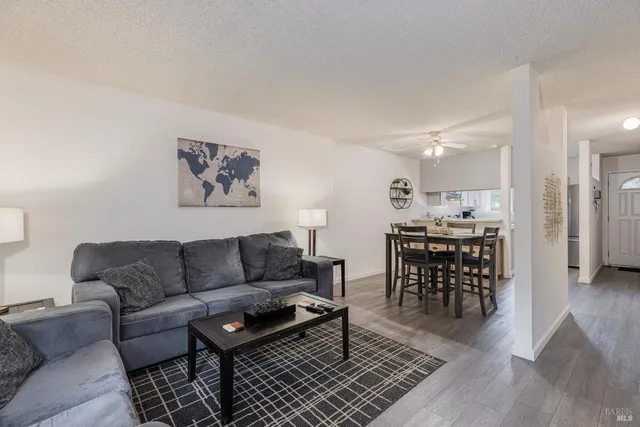 a living room with furniture a wooden floor and a kitchen view
