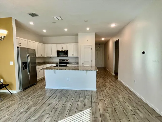 a large kitchen with stainless steel appliances granite countertop a large counter top a stove and a refrigerator