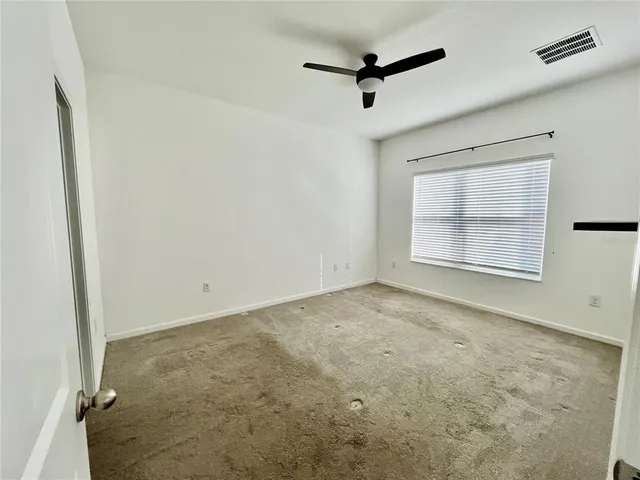 an empty room with windows and fan