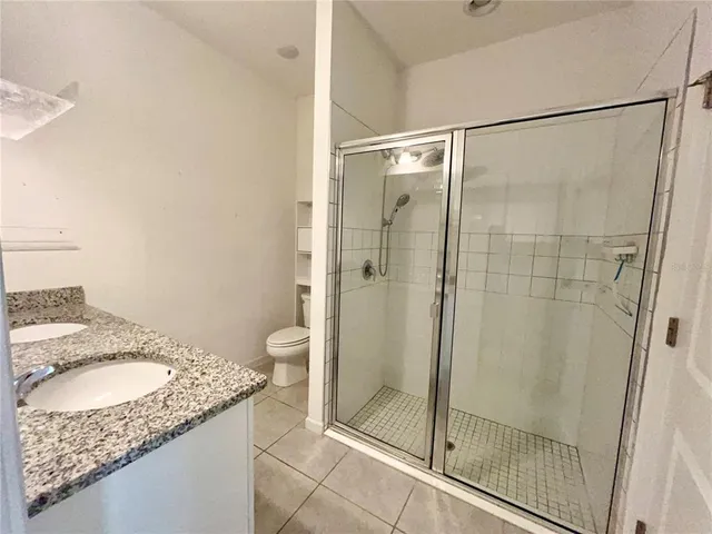 a bathroom with a granite countertop shower a sink and toilet
