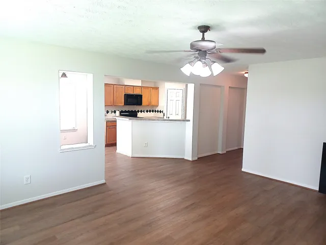 a view of a kitchen with a stove wooden floor cabinets and a ceiling fan
