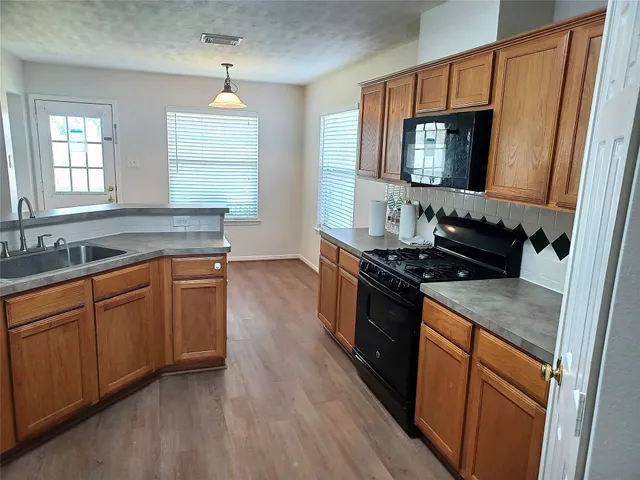 a kitchen with granite countertop a sink and a stove top oven with wooden floor