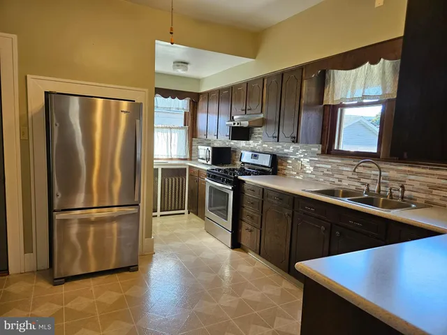 a kitchen with stainless steel appliances granite countertop a refrigerator a sink dishwasher a stove with wooden floor and cabinets