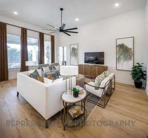 a living room with furniture a flat screen tv and a floor to ceiling window