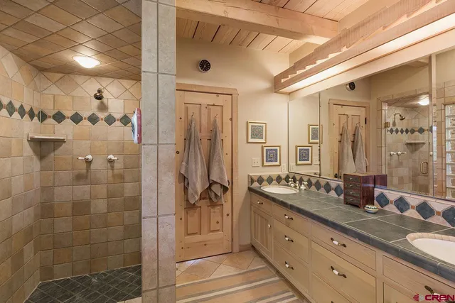 a spacious bathroom with a double vanity sink a large mirror and shower