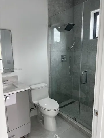 a bathroom with a granite countertop sink a toilet and shower