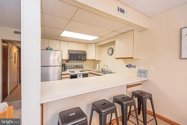 a kitchen with a sink a refrigerator and chairs