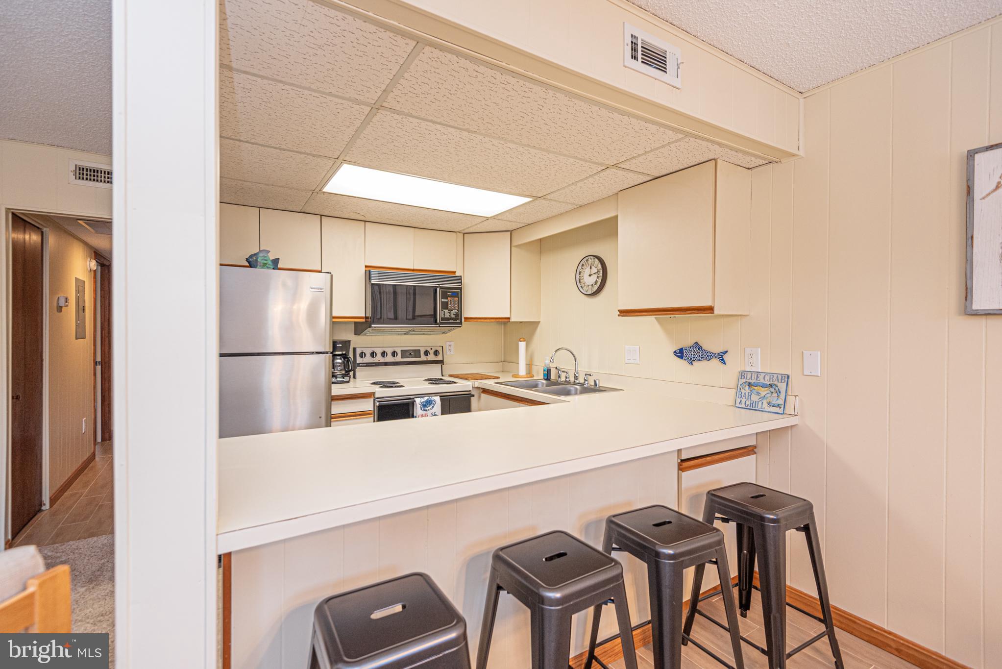 14405 Tunnel Avenue, Unit 112 Ocean City, MD 21842 - Photo 8 of 32 a kitchen with a sink a refrigerator and chairs