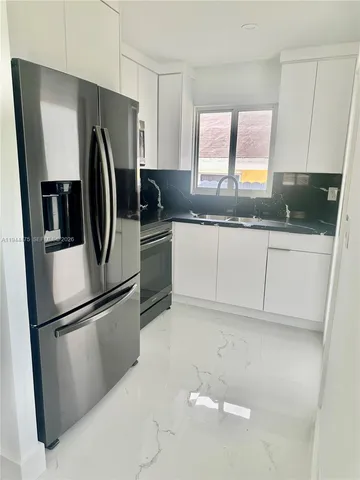 a kitchen with granite countertop a refrigerator and a sink