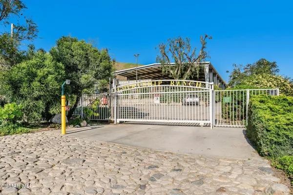 a view of a brick house with a small yard and large trees