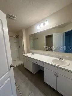 a bathroom with a double vanity sink and mirror with shower