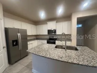 a kitchen with stainless steel appliances granite countertop a sink refrigerator and microwave