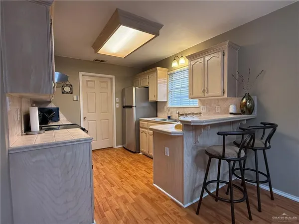 a kitchen with kitchen island a stove a sink a refrigerator dining table and chairs
