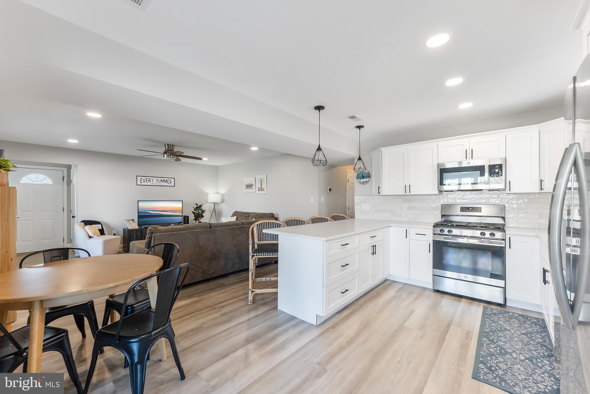 12 Lighthouse Drive, Unit A Brigantine, NJ 08203 - Photo 7 of 32 a kitchen with stainless steel appliances kitchen island granite countertop a stove a sink a refrigerator and white cabinets with wooden floor