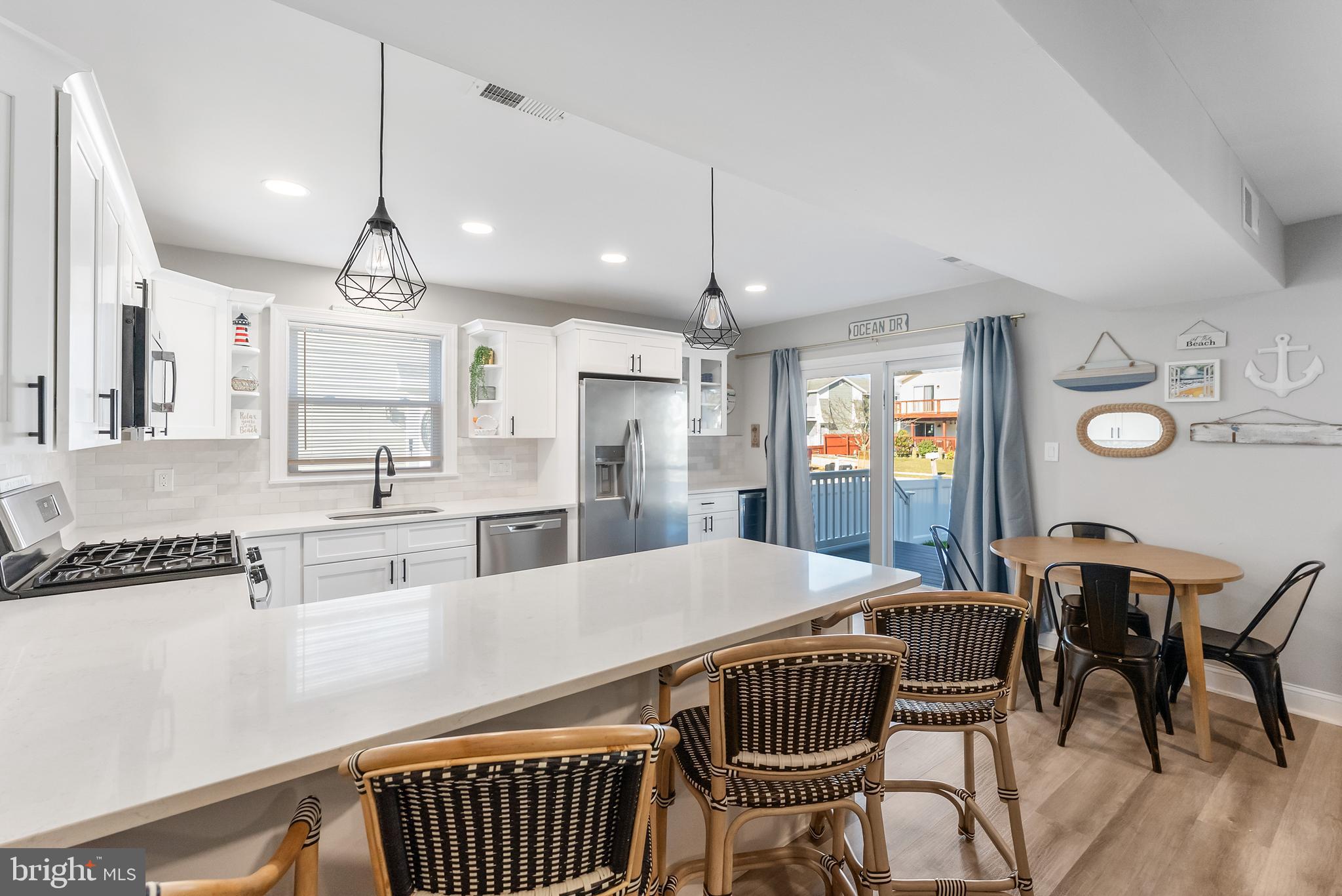 12 Lighthouse Drive, Unit A Brigantine, NJ 08203 - Photo 8 of 32 a kitchen with stainless steel appliances kitchen island granite countertop a dining table chairs and a refrigerator