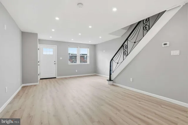 a view of an empty room with wooden floor and stairs