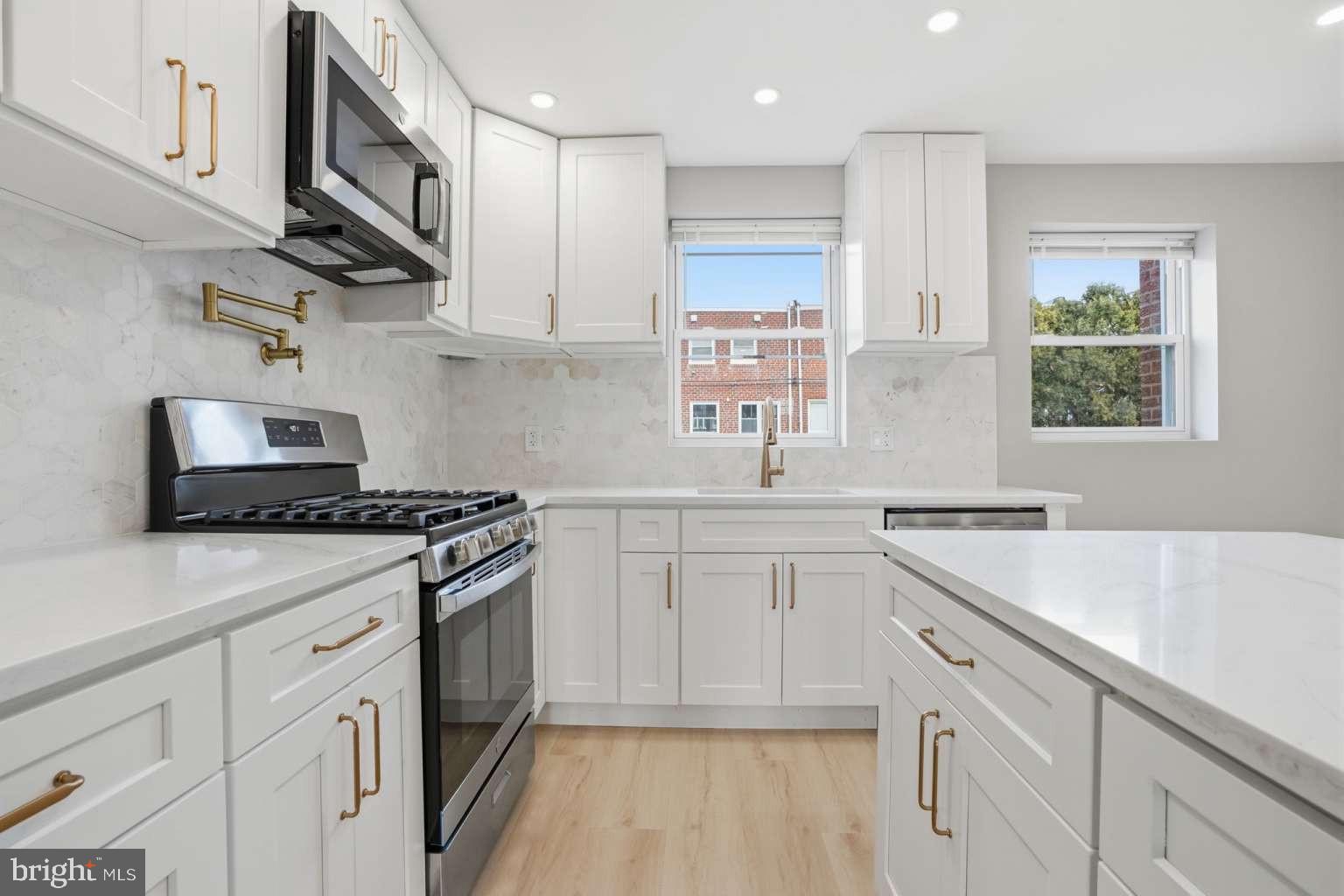 8653 Rugby Street Philadelphia, PA 19150 - Photo 8 of 45 a kitchen with stainless steel appliances granite countertop a sink stove a refrigerator and white cabinets with wooden floor