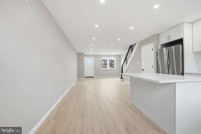 a view of an empty room with wooden floor and stairs