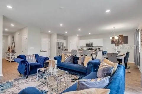 a living room with furniture kitchen view and a wooden floor