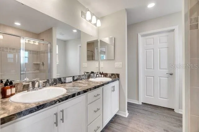 a bathroom with a granite countertop double sink and a mirror