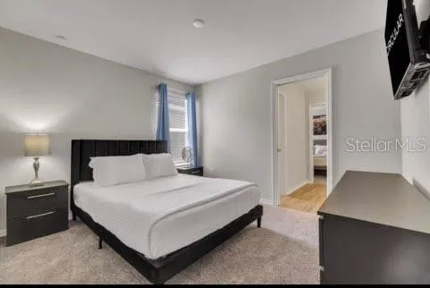 a large bedroom with a bed and flat tv screen on the dresser
