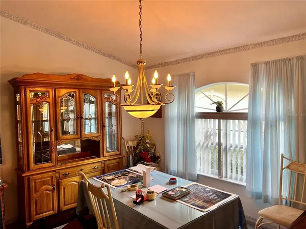 a view of a dining room with furniture a chandelier and large windows