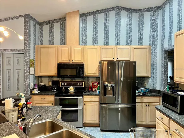 a kitchen with a dining table chairs cabinets and stainless steel appliances